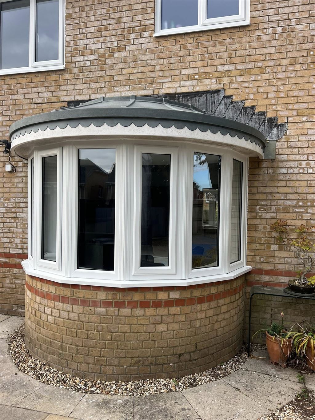 White uPVC bow window with a lead-effect roof